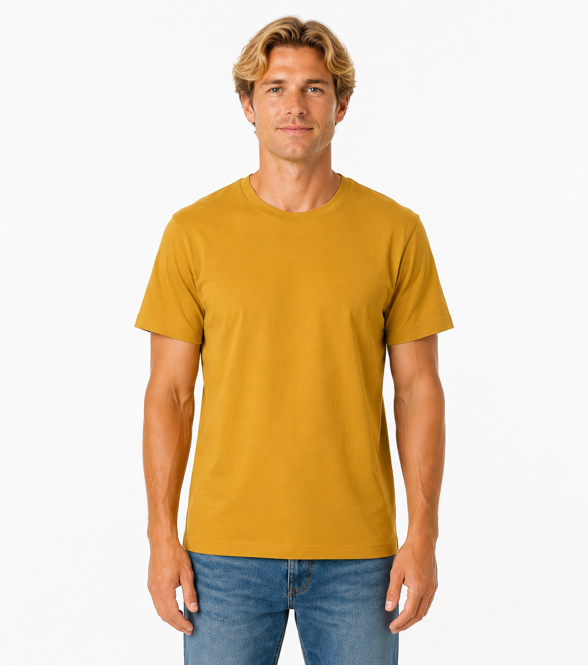 A man wearing a solid mustard yellow crew-neck t-shirt and blue jeans, standing against a plain white studio background.