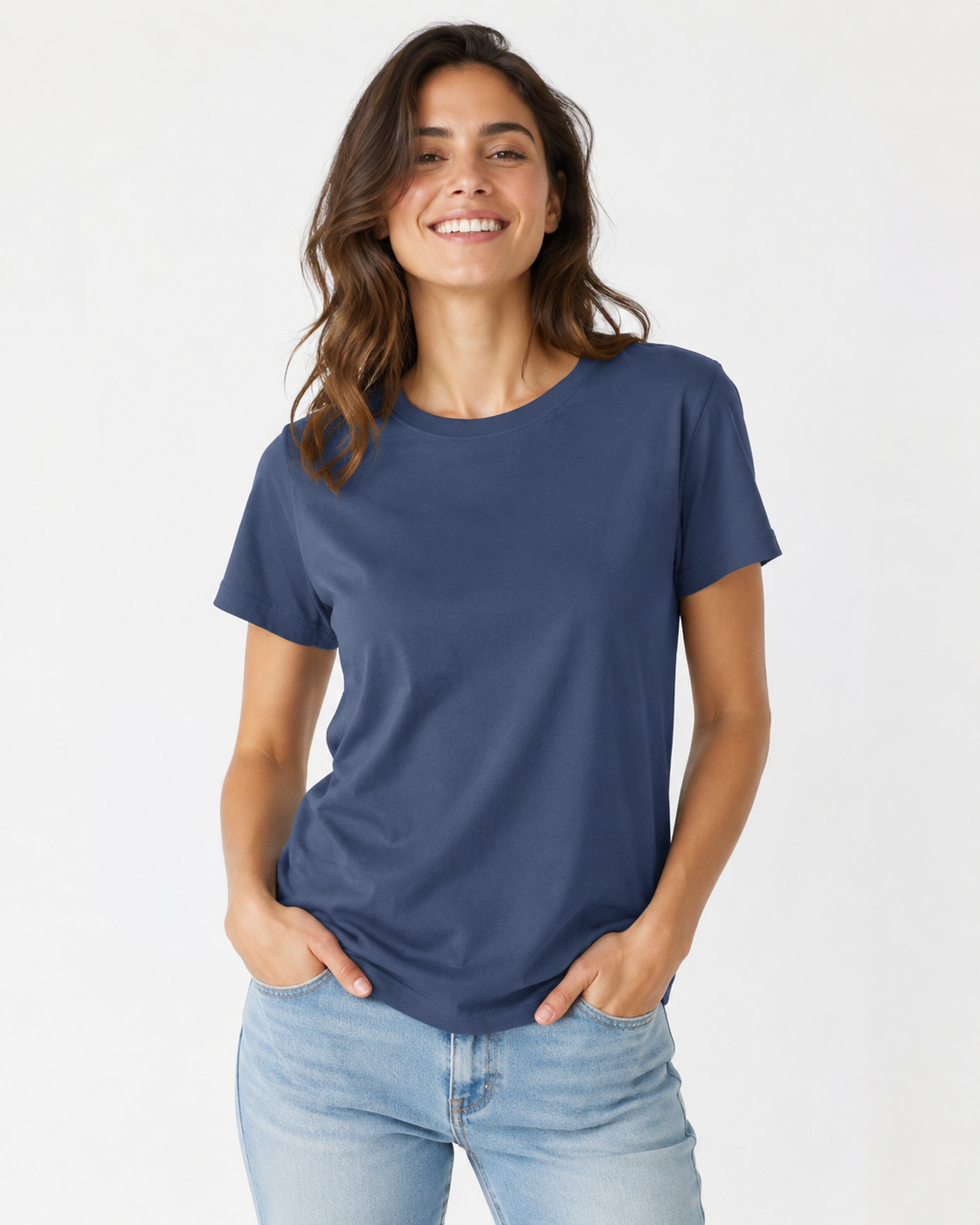 A woman wearing a solid indigo blue short-sleeve crewneck t-shirt and light wash blue jeans, standing against a plain white studio background.