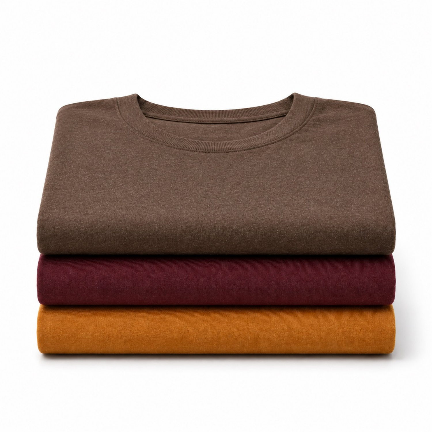 Three folded crewneck t-shirts stacked vertically on a white background, in brown, burgundy, and mustard yellow.