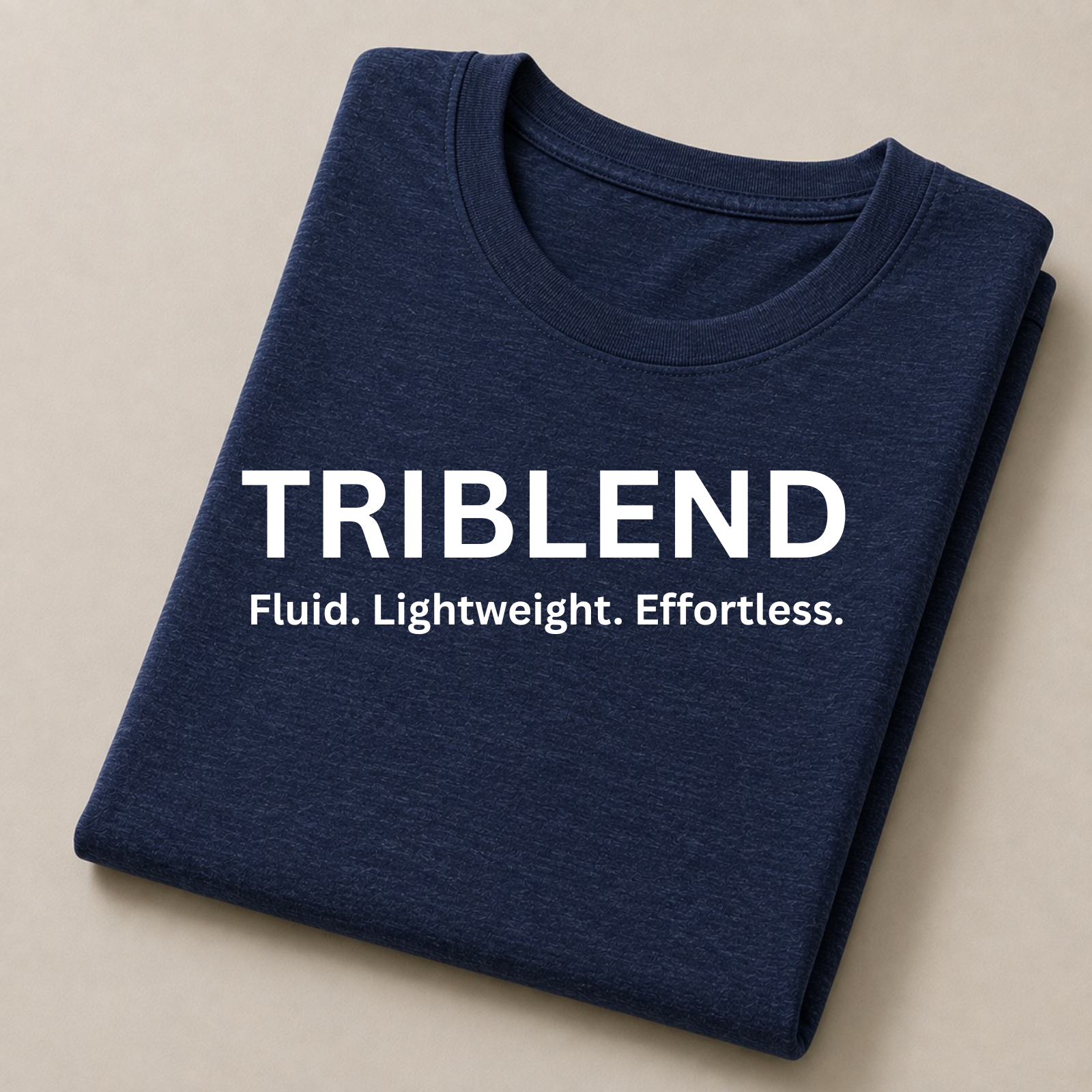 A folded navy blue triblend  t-shirt with white printed text reading 'TRIBLEND' and 'Fluid. Lightweight.